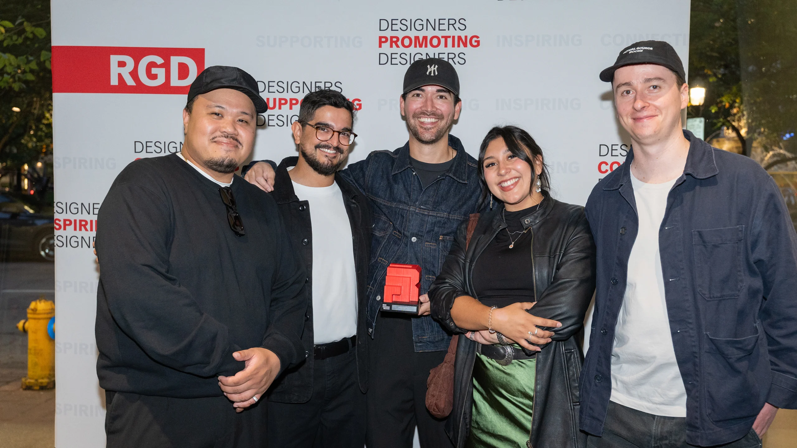 The ZAK team and award winners posing together at the RGD event, holding the red trophy.