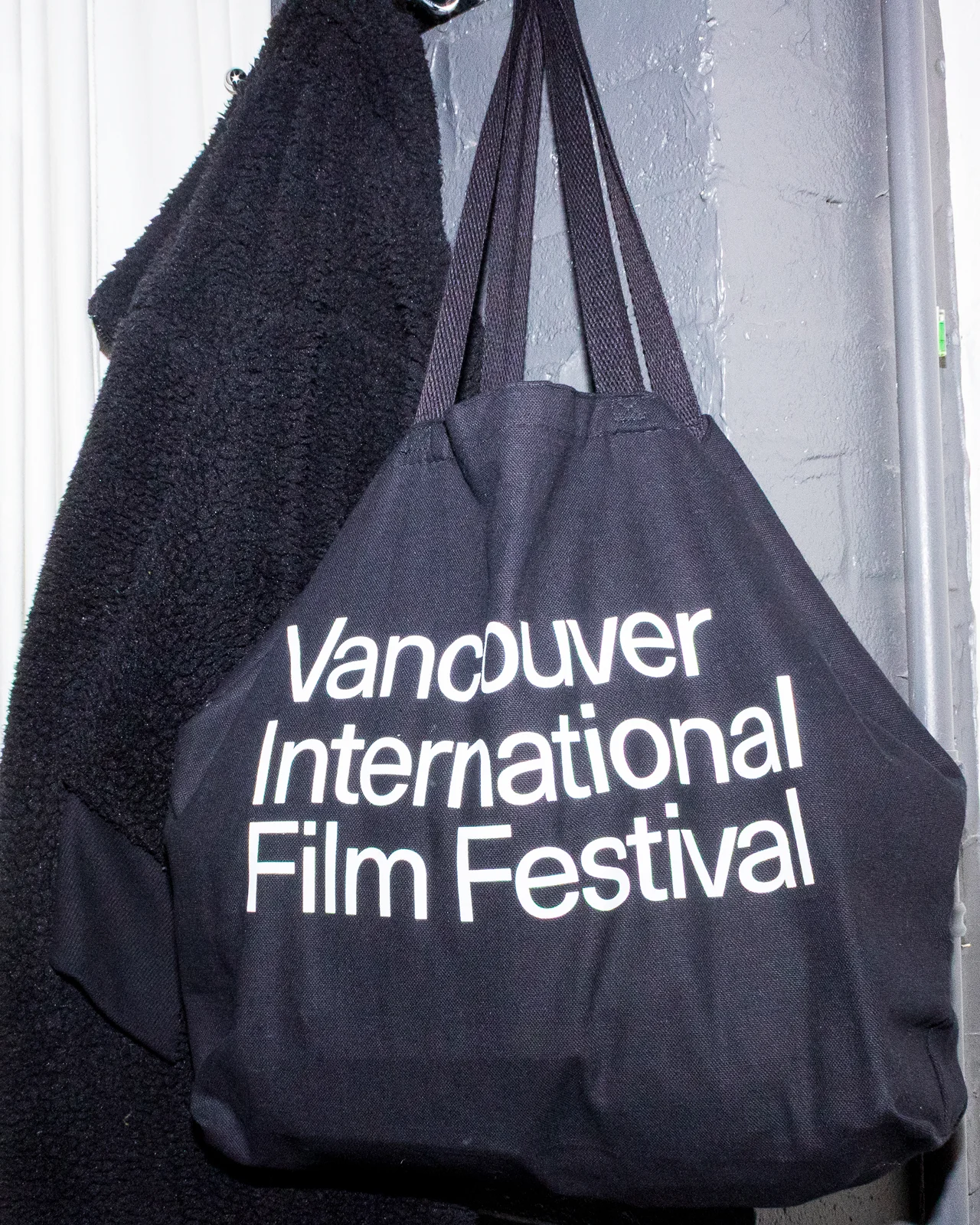 Black canvas tote bag with bold white modernist typography for the Vancouver International Film Festival 2025.