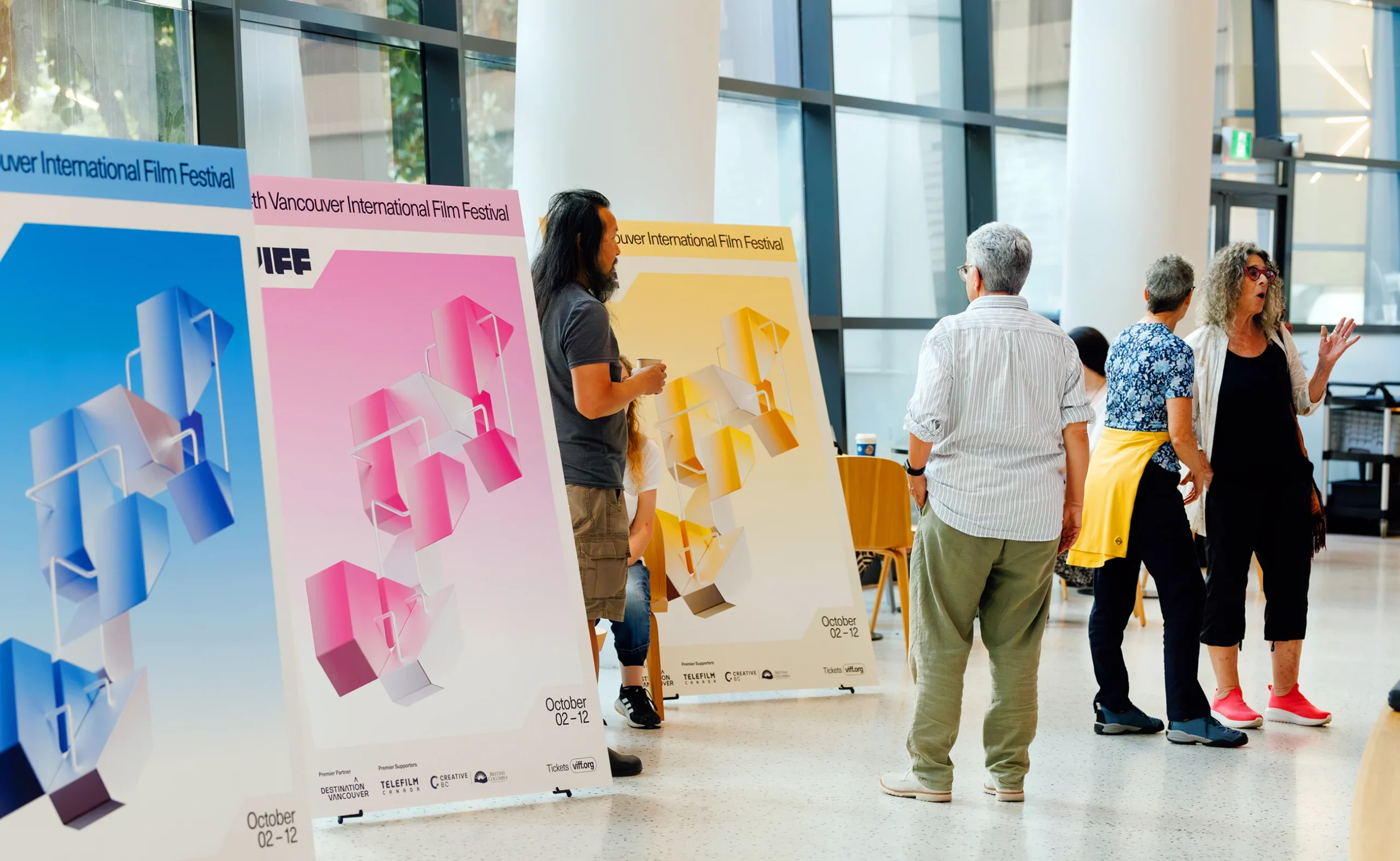 Large scale 3D festival posters in pink, yellow, and blue at a Vancouver International Film Festival 2025 venue.