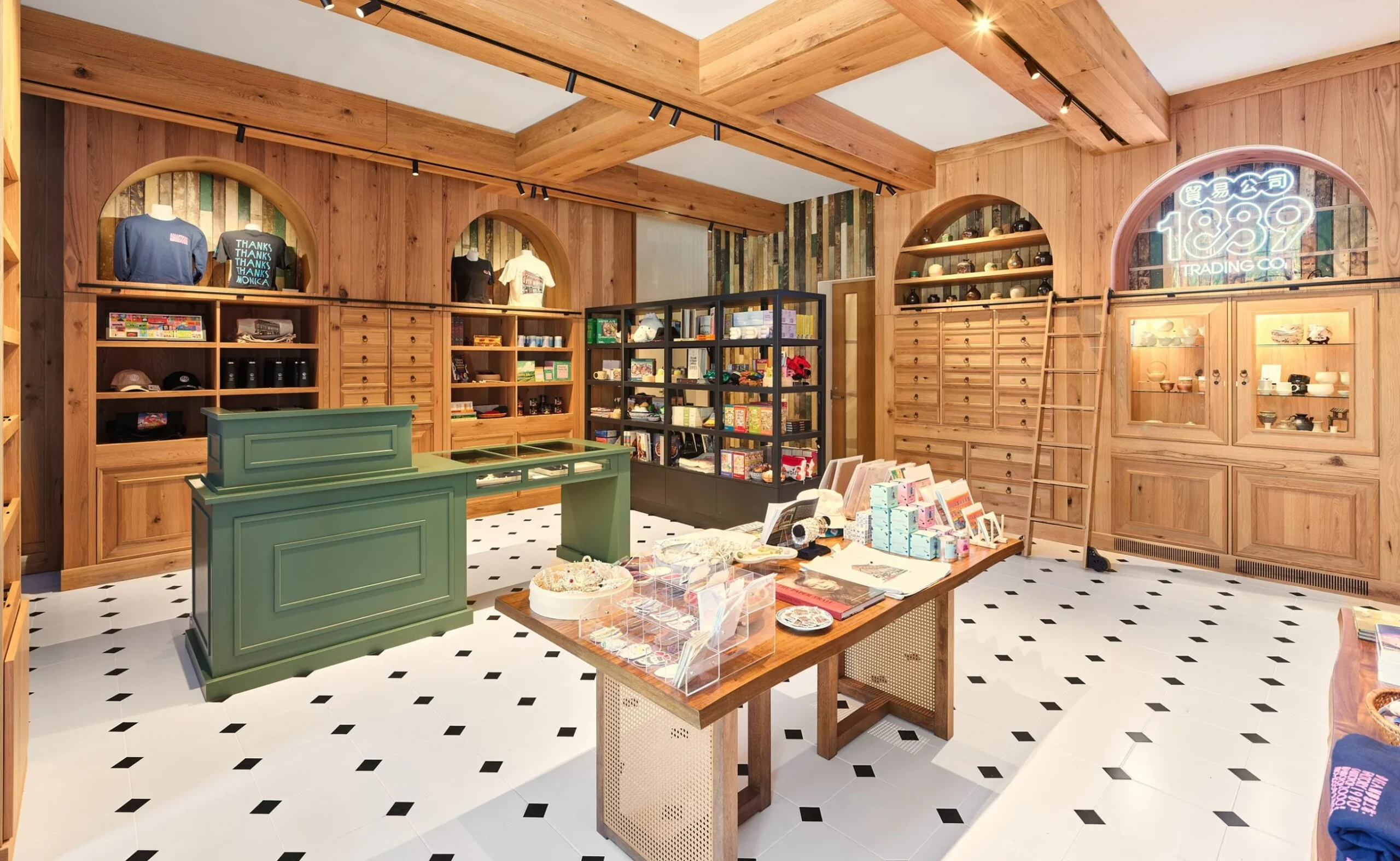 Modern retail interior with light wood cabinetry, apothecary drawers, and an arched neon 1889 Trading Co. logo.